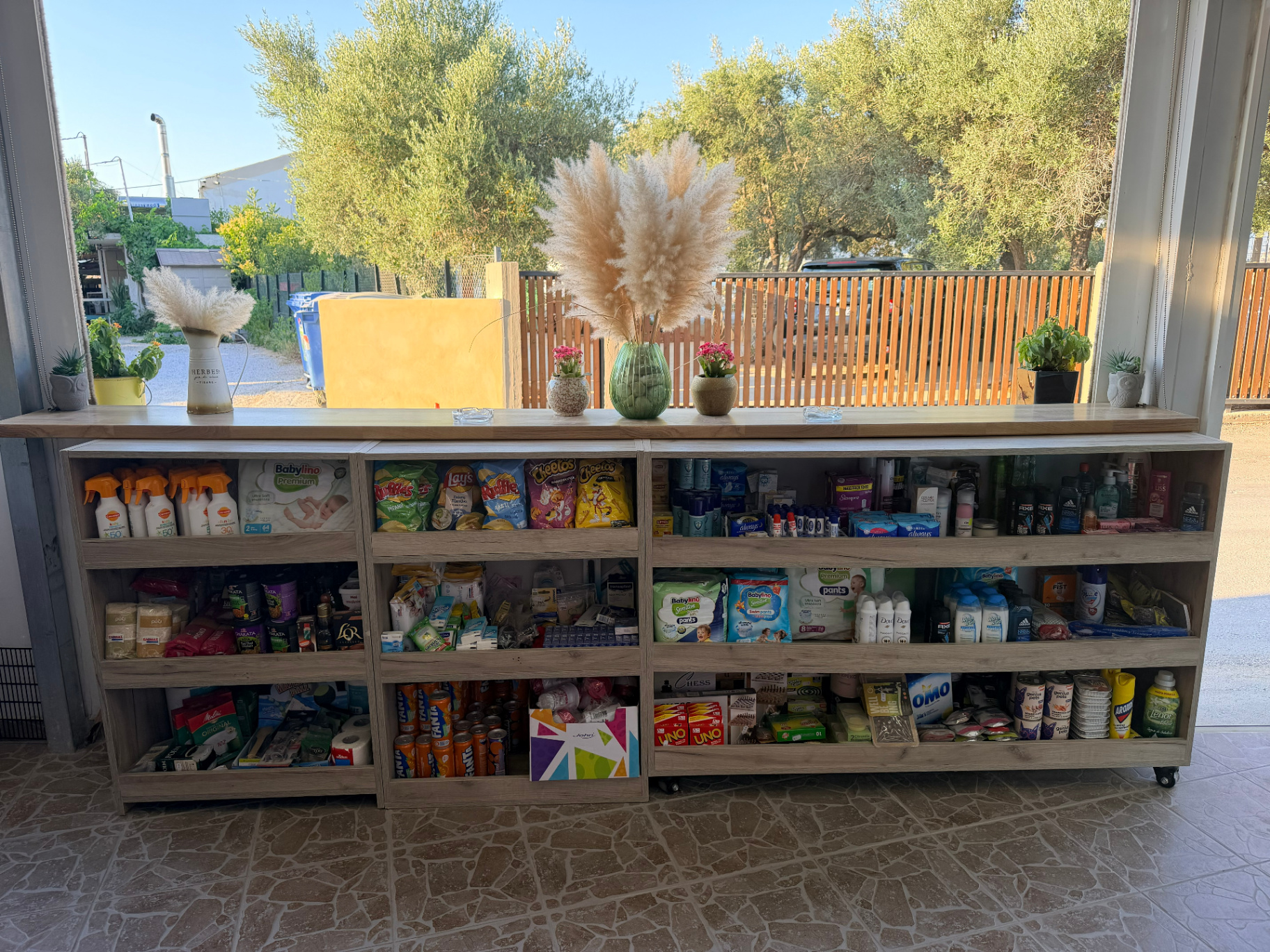Everyday essentials shelves with sunscreen diapers toiletries and household items at AMOS SEASIDE mini market near JW Marriott Crete