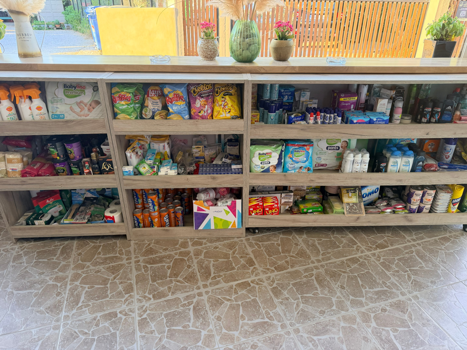 Mini market essentials shelf close up with Carroten sunscreen Babylino diapers snacks and personal care Marathi Chania
